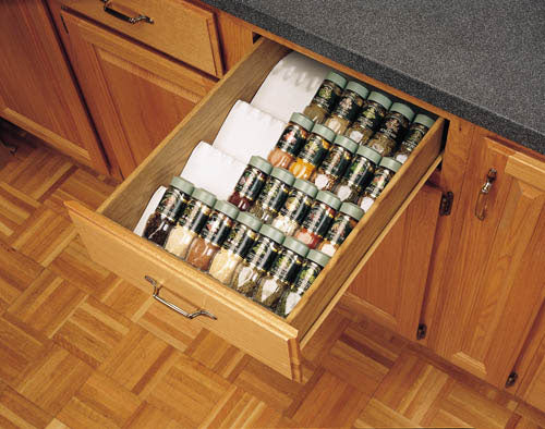 Spice drawer insert with tiered design holding organized spice jars in a wooden kitchen cabinet drawer